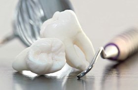 Two extracted wisdom teeth next to dental instruments