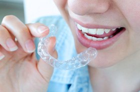 Person holding Invisalign aligner close to her teeth