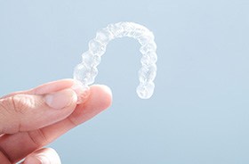 Person’s hand holding a clear aligner