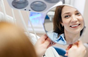 Dental patient admiring her smile in mirror