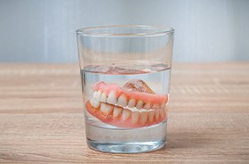 Dentures in cup of water on tabletop