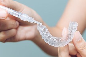 Woman placing whitening formula in custom tray