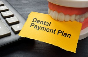 Tooth model holding paper that says, “dental payment plan”
