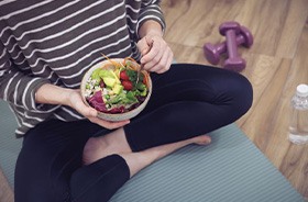 Woman eating a healthy meal while sitting on the floor