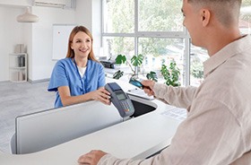 Man paying for service at dental office front desk
