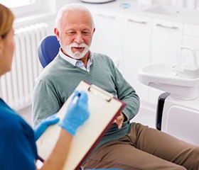 Dental team member taking notes during patient consultation