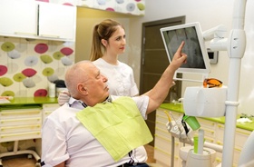 Dentist and senior patient discussing candidacy for tooth replacement