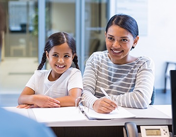 Smiling woman with her daughter at dental office front desk