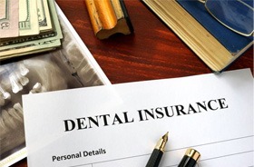 Dental insurance document next to X-ray and cash