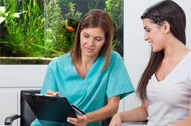 Patient and dental team member conversing over clipboard