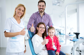 Parents and daughter giving thumbs up for family dentistry
