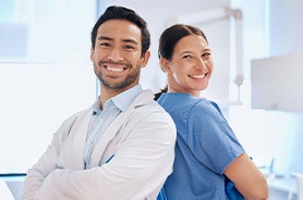 Happy dentist and team member standing back to back