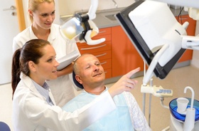 Dental team and patient discussing candidacy for implant dentures