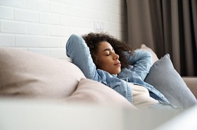 Woman resting on sofa to manage implant surgery side effects