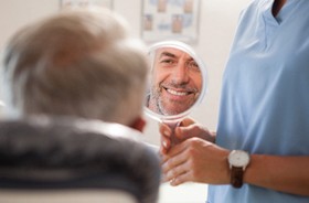 Male patient admiring his new restorations in mirror