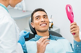 young man smiles at his Woodbridge implant dentist after treatment