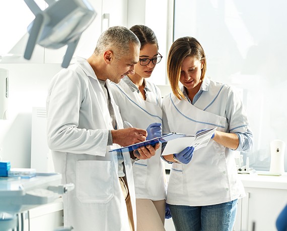 Three dental team members looking at tablet computer