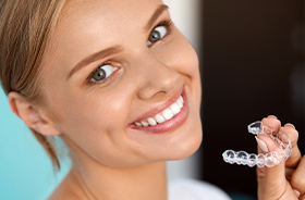 Smiling woman holding Invsialign tray