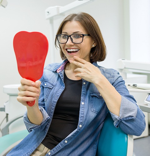 Dental patient looking at her smile in mirror