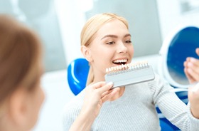 female dental patient admiring her white teeth after smile makeover