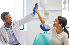 Happy patient high-fiving her dentist