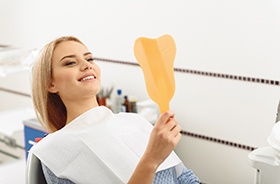 Happy dental patient admiring the results of her cosmetic treatment