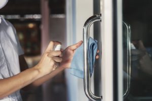 dental team member disinfecting practice door for practice safety