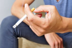 Man with cigarette, thinking about smoking and dental implants