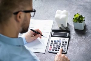 Man using calculator to budget for root canal therapy