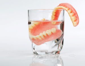 Dentures resting in glass of water