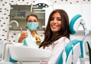 Smiling dental patient with happy dentist in the background