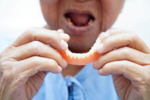 Senior person holding their lower denture 